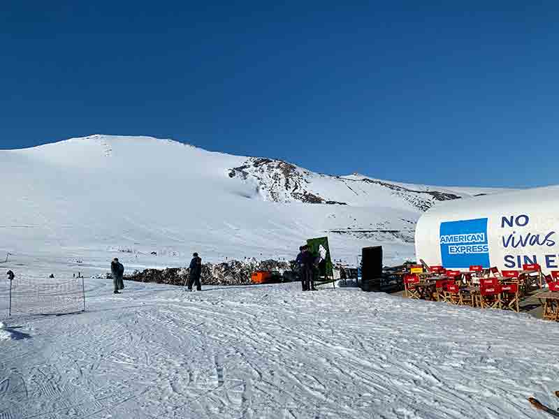 Pessoas na entrada do centro de ski de Corralco, no Chile, em dia de céu azul