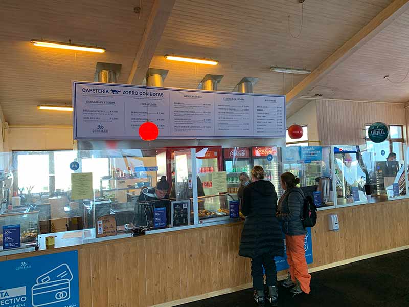 Pessoas fazem pedido em restaurante em frente à pista de ski com preços acima