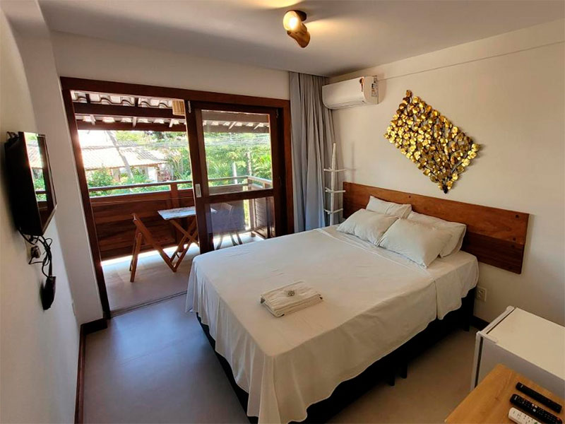 Quarto da Pousada Ana do Forte com cama de casal, varanda, TV e ar-condicionado