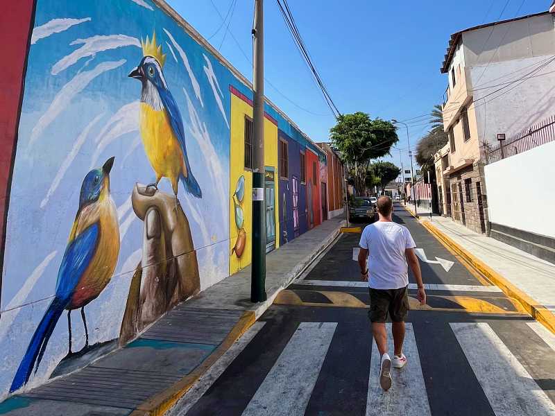 Homem de costas caminha em rua com grafites em Barranco, bairro que vale entrar no roteiro de o que fazer em Lima
