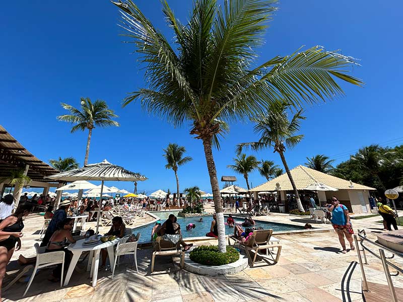 Pessoas em mesas na beira da praia no beach club Ponta do Maragogi