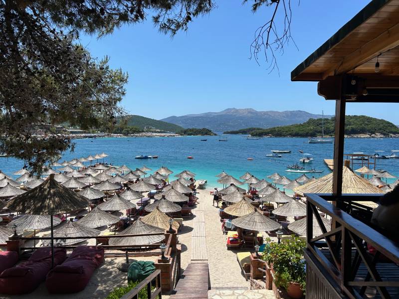 Praia de Ksamil, na Albânia, com mar azul e guarda-sóis lotando a areia