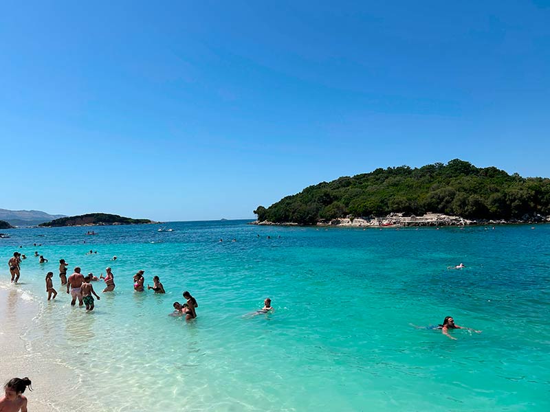 Pessoas curtem o mar azul da Lori Beach, uma das praias de Ksamil