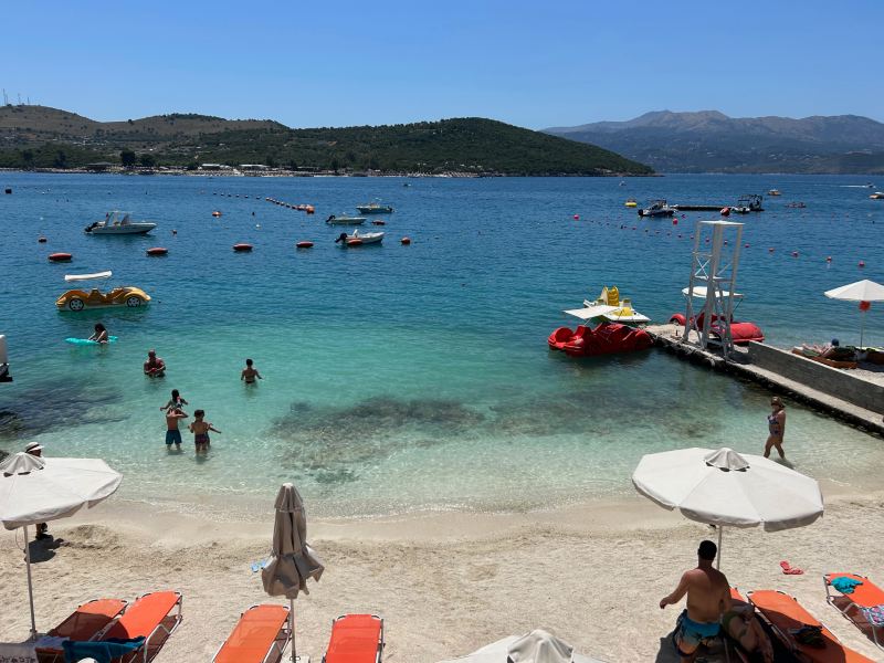 Pessoas se divertem no mar esverdeado da Bora Bora Beach, em Ksamil