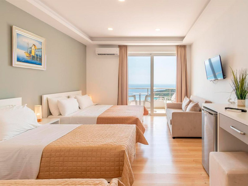 Quarto do Aphrodite Hotel, dica de onde ficar em Himara, com duas camas, sofá,  TV e varanda