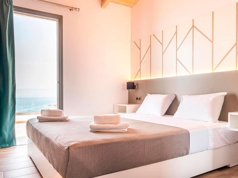 Quarto da First House com cama de casal e varanda com vista para o mar