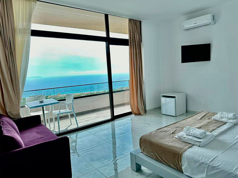 Quarto da Wait'n Sea, dica de onde ficar em Himara, com cama de casal, TV e varanda com vista para o mar