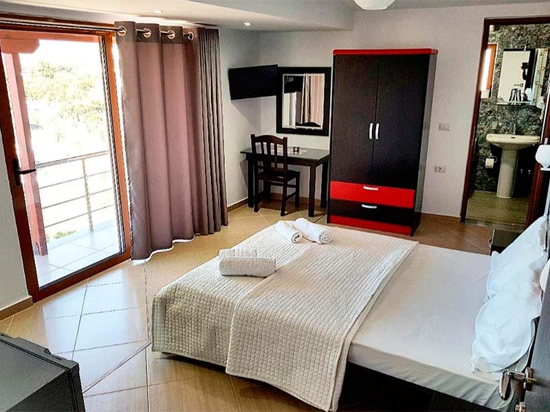 Quarto do Hotel Lula, dica de onde ficar em Ksamil, na Albânia, com cama de casal e guarda-roupa preto e vermelho