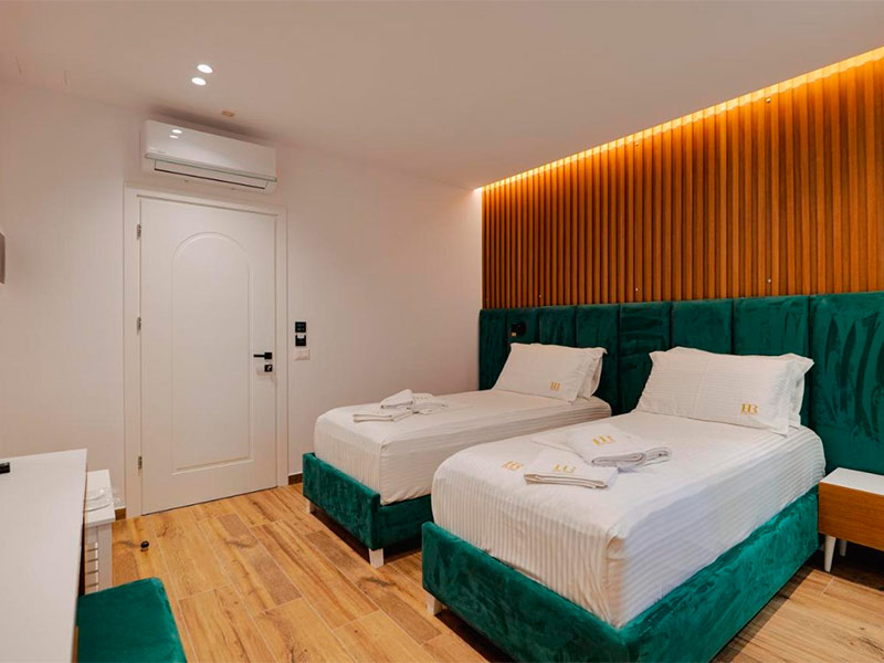 Quarto do Hotel Renato com duas camas de solteiro e detalhes em verde