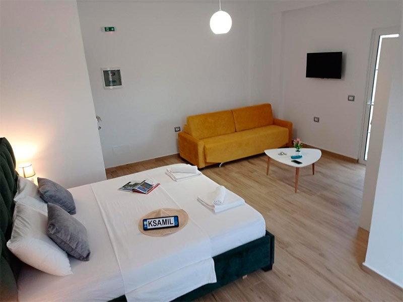 Quarto do Vasiliu Boutique Hotel com cama de casal, TV e sofá mostarda