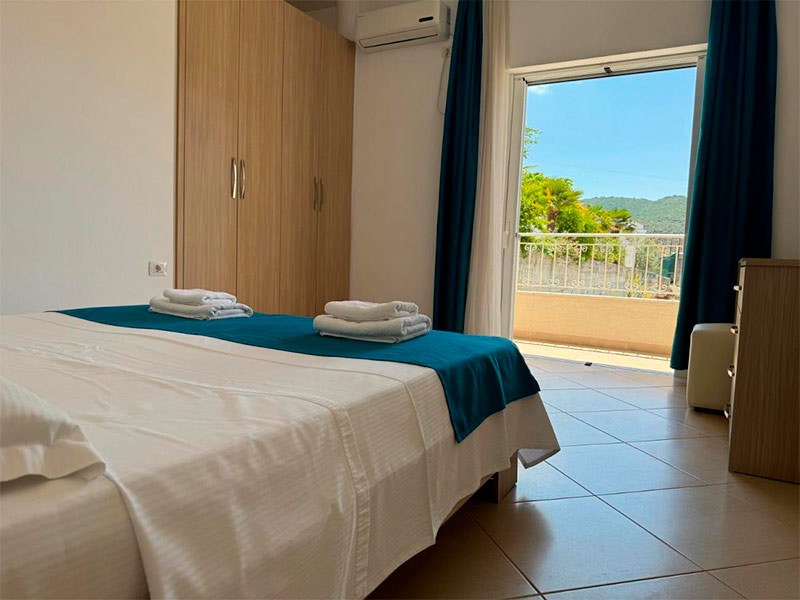 Quarto do Villa August, dica de onde ficar em Ksamil, com cama de casal, guarda-roupa e varanda