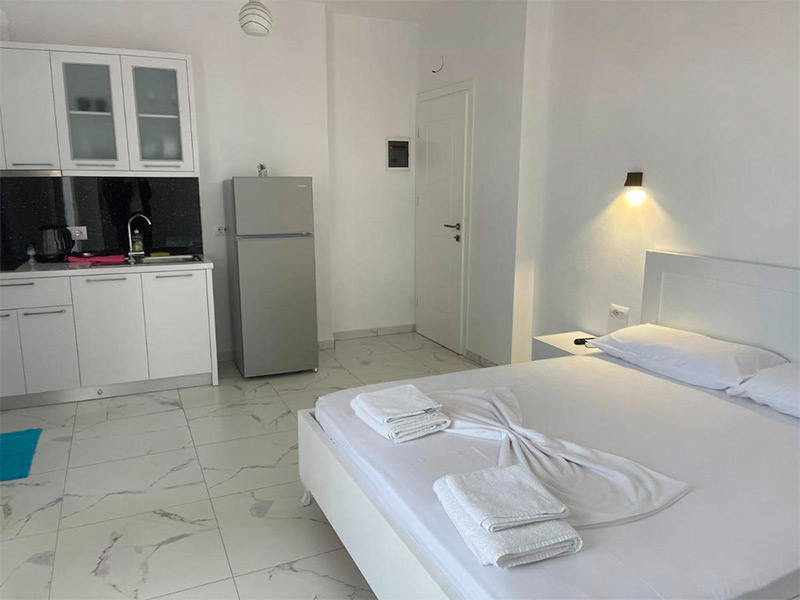 Quarto do Villa Denis, dica de onde ficar em Ksamil, com cama de casal e cozinha com geladeira