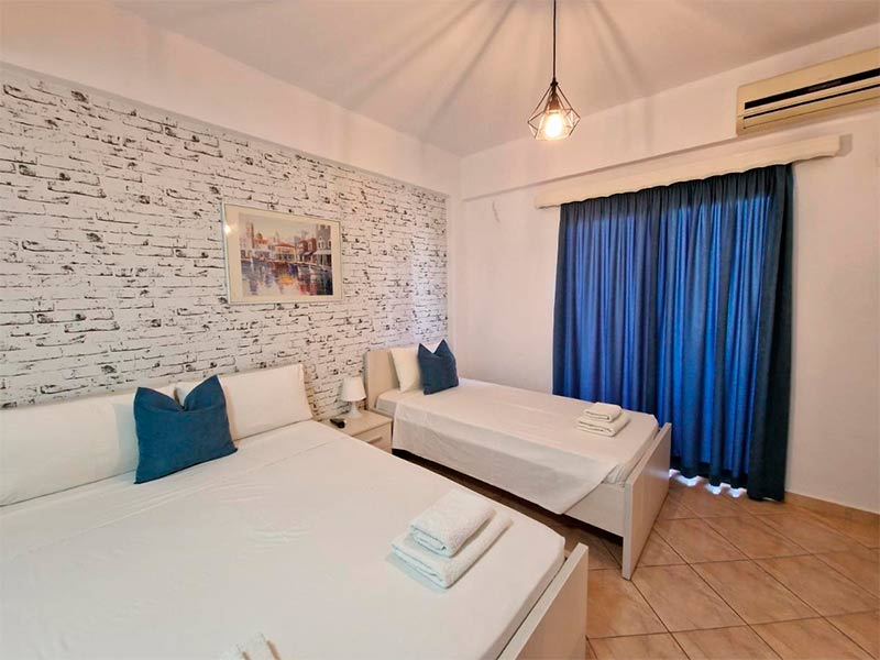 Quarto do Villa White com cama de casal e cama de solteiro e cortina azul fechada