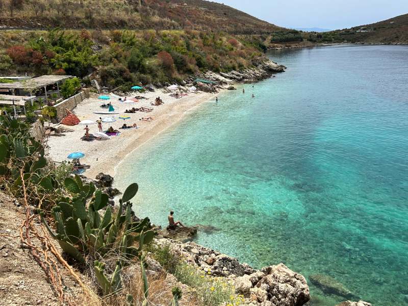 Vista de cima de praia em Himara com mar esverdeado