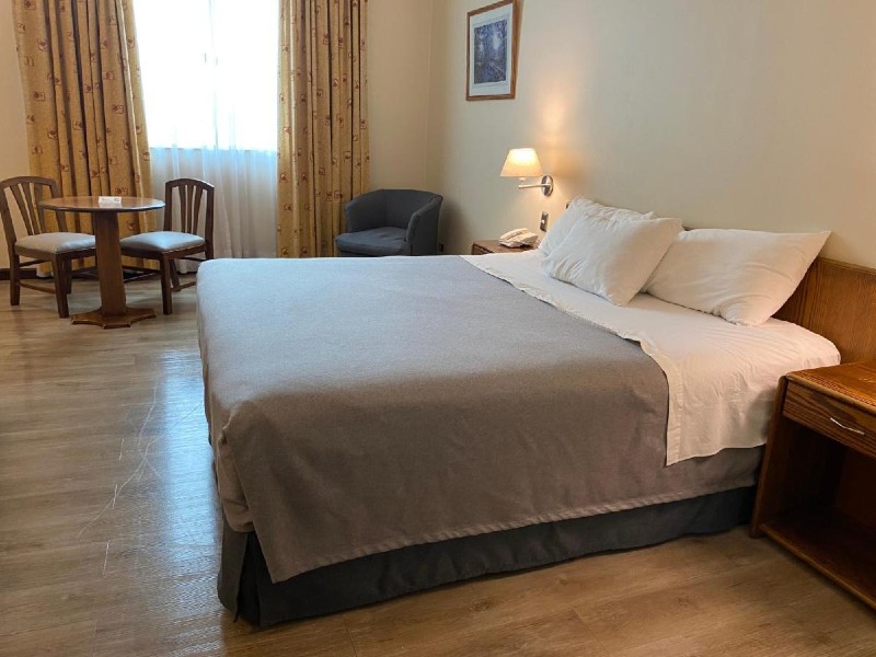 Quarto do Hotel Diego de Almagro Aeropuerto, dica de onde ficar no aeroporto de Santiago, com cama de casal, poltrona e mesa