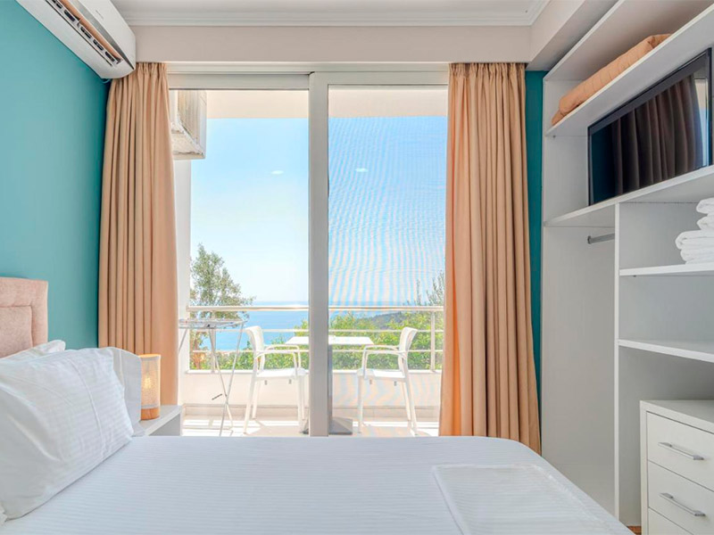 Quarto do Aphrodite Garden com parede verde, cama de casal e vista para o mar