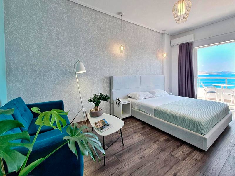 Quarto do Hotel JoAn, dica de onde ficar na Albânia, com cama de casal, piso de madeira e varanda com vista para o mar