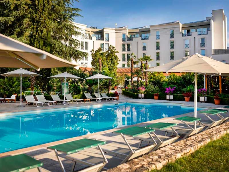 Piscina do Rogner Hotel, dica de onde ficar na Albânia, com espreguiçadeiras vazias em dia de céu azul