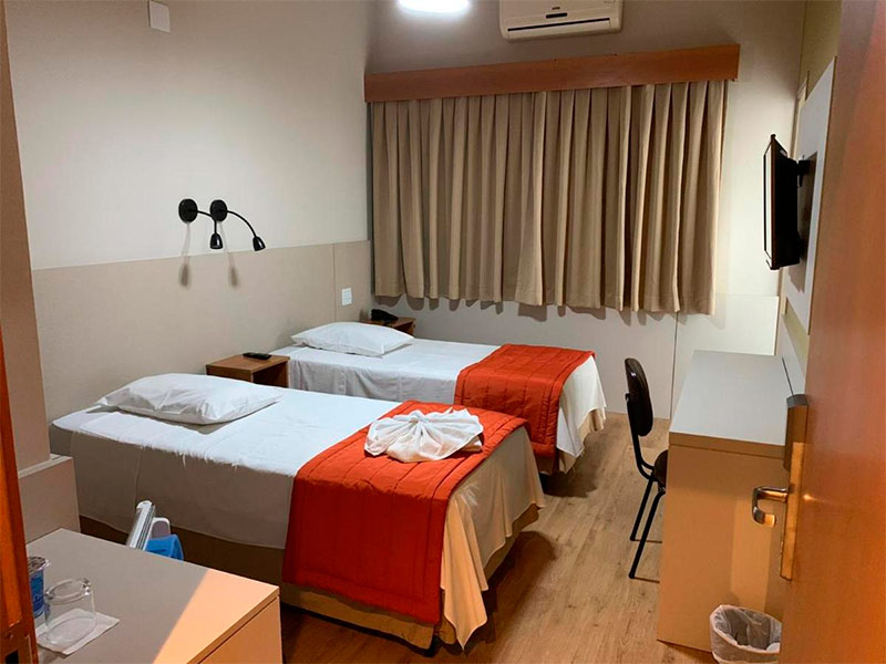 Quarto do Hotel Cisne, dica de onde ficar perto do Allianz Parque, com duas camas de solteiro, TV, mesa de trabalho e ar-condicionado