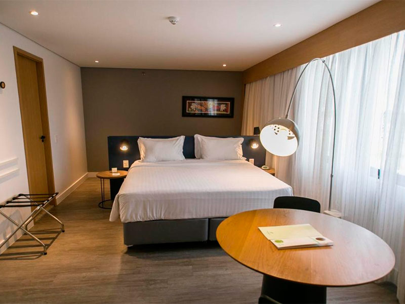 Quarto do Holiday Inn Parque Anhembi com cama de casal, parede escura e mesa de trabalho