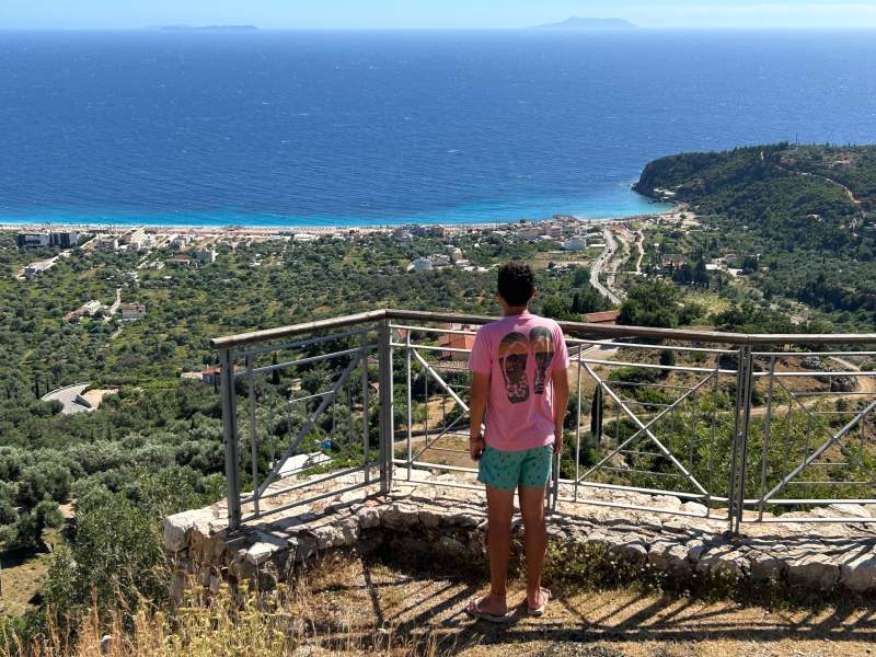 Homem observa praia em Himara vista de castelo