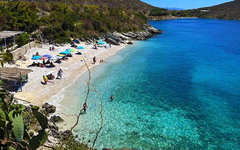 Vista de cima do mar esverdeado da Porto Palermo Beach, em Himara