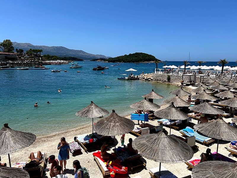 Praia apertada de Ksamil com guarda-sóis na areia