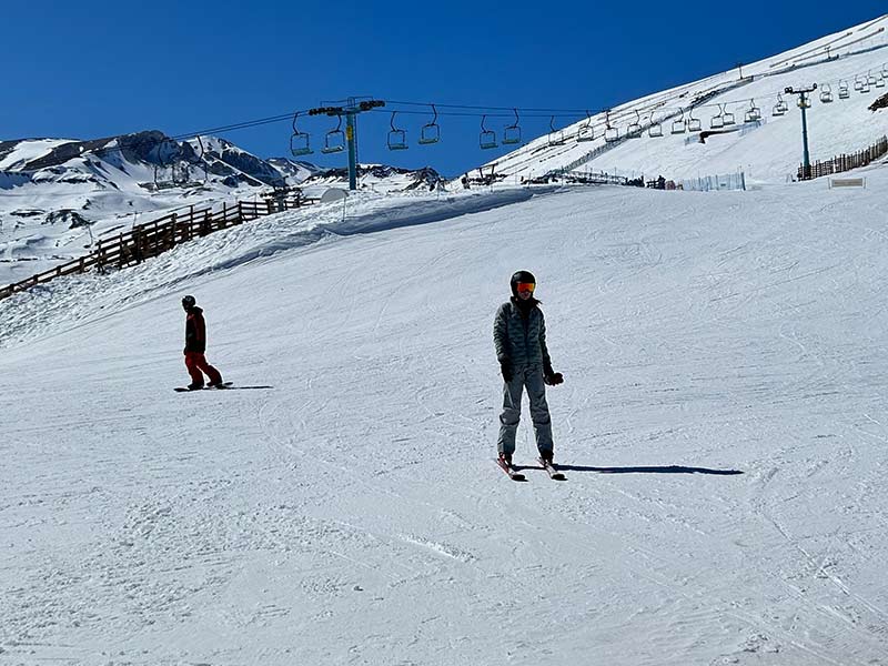 Pessoas esquiando em pista no Chile em dia de céu azul