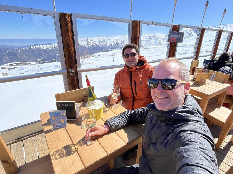 Amigos tomam vinho com vista para as montanhas com neve em restaurante em El Colorado, no Chile