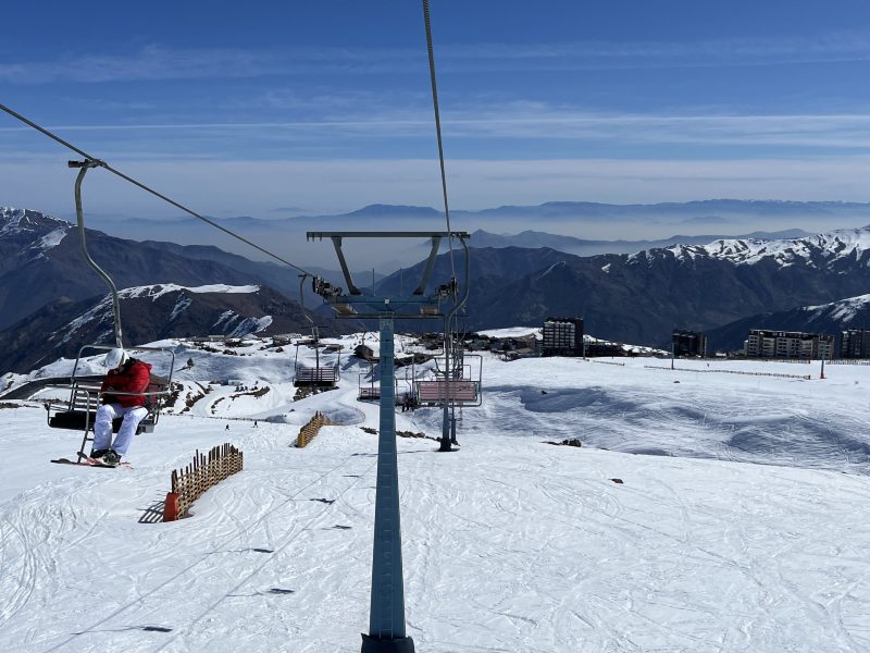 Pessoas subindo e descendo no teleférico de El Colorado, no Chile, em dia de céu azul