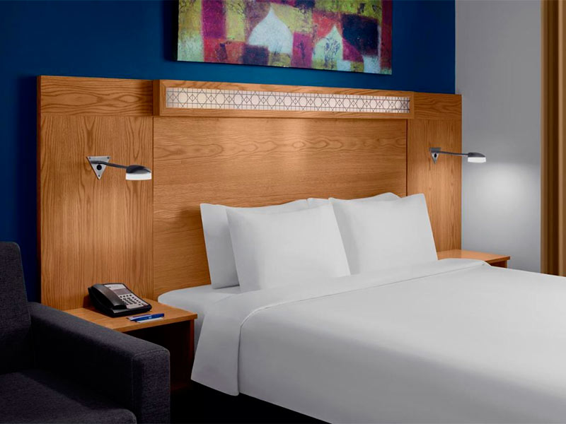 Quarto do Holiday Inn Express, dica de hotel no aeroporto de Dubai, com painel de madeira e cama de casal