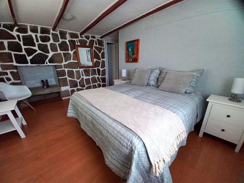 Quarto do El Colorado Lodge com cama de casal, cadeira e mesa de cabeceira