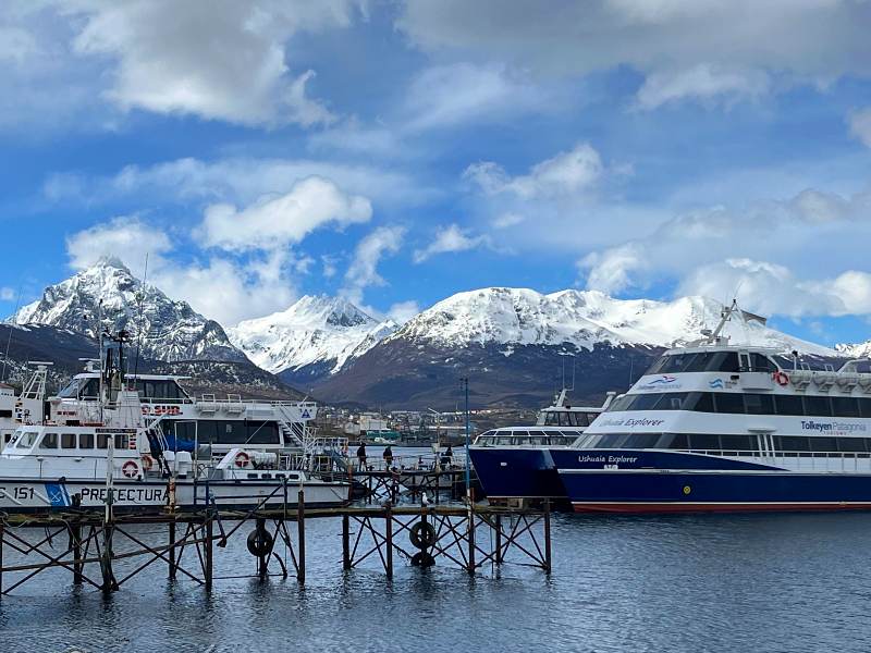 Quando ir pro Ushuaia: Porto da cidade com barcos e montanhas com neve ao fundo