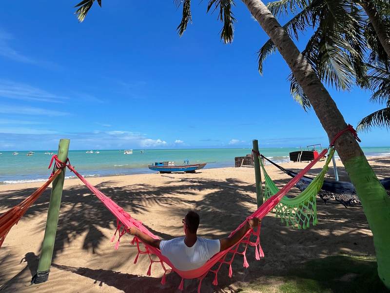 Homem sentado em rede na praia de Japaratinga, em Alagoas