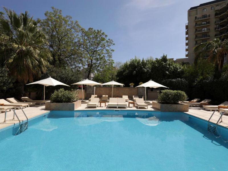 Piscina e espreguiçadeiras vazias com prédio ao fundo do Park Hyatt, dica de onde ficar em Mendoza