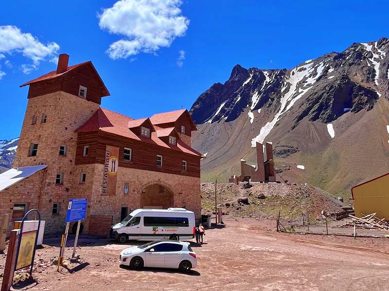 Vista de prédio em Las Cuevas com os Andes nevados ao fundo, na divisa de Argentina e Chile