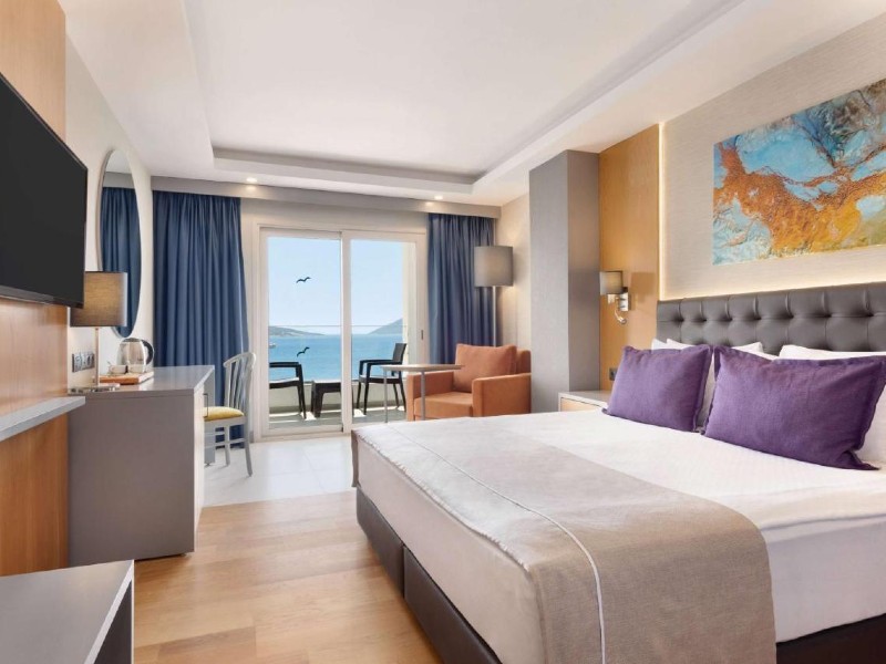 Quarto do La Quinta by Wyndham, dica de onde ficar em Bodrum, com cama de casal, almofadas roxas, TV e varanda