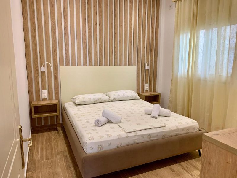 Quarto do Duka Apts, dica de onde ficar em Saranda, com cama de casal e cortina amarela