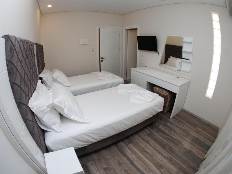 Quarto do Ramo Hotel com duas camas de solteiro, TV e porta encostada