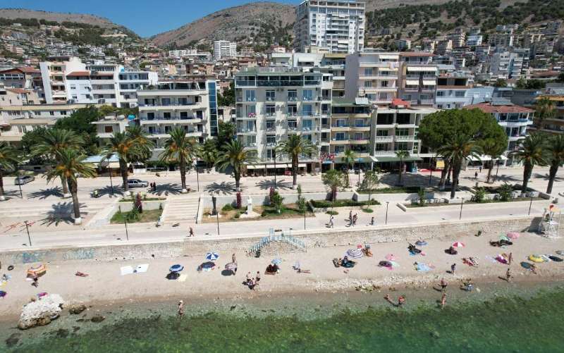 Parte externa do Republika Hotel em frente à praia com mar esverdeado