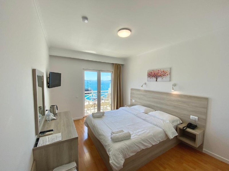 Quarto do Sun N Blue Hotel, dica de onde ficar em Saranda, com cama de casal,  TV e varanda com vista para o mar